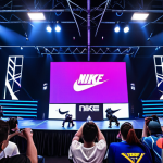 **

"Victory Goddess Nike" global e-sports tournament scene. Focus on competitive gaming atmosphere, with players intensely focused on screens, vibrant lighting, and audience excitement. Include the "Nike" logo subtly in the background.

**